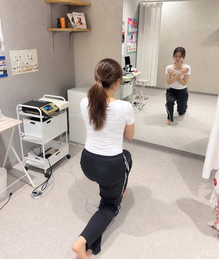 鏡の前で加圧ベルトを着けてスクワットをしている様子